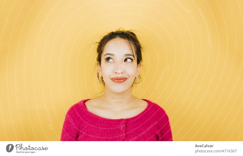 Young african woman looking away from camera naughty thinking about something, posing isolated over yellow color wall background. Daily expressions with copy space in studio.