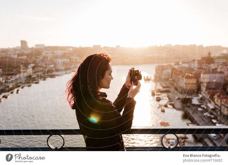 woman in Porto bridge taking pictures with camera at sunset. Tourism in city Europe. travel porto tourist enjoy 30s relax holidays vacation urban high