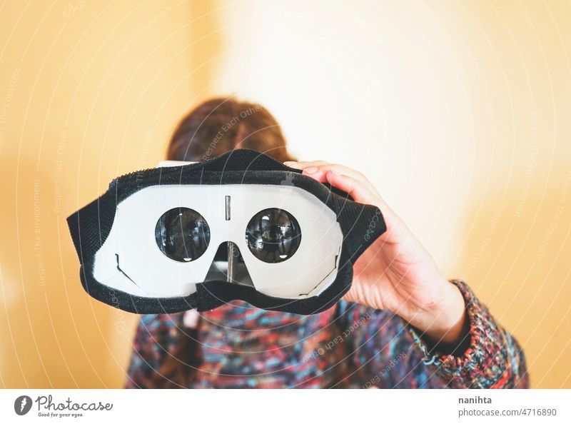 Forced perspective image of a young woman holding the lenses of a vr glasses of cardboard metaverse inside technology sustainability playful gamer weird nerd