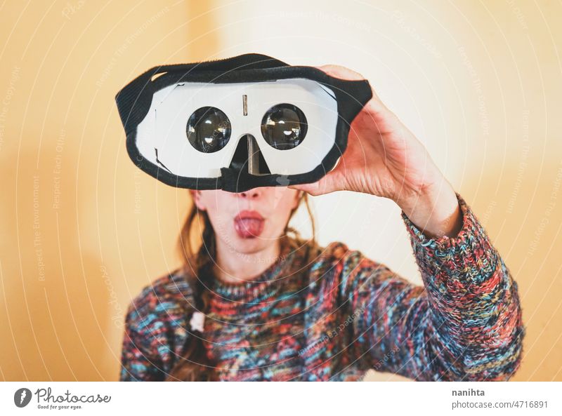 Forced perspective image of a young woman holding the lenses of a vr glasses of cardboard metaverse inside technology sustainability playful gamer weird nerd