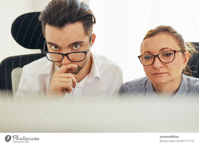 Two business people discussing financial data looking at computer screen. Entrepreneurs working hard sitting at computere screen in office. People having deadline working together