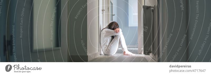 Woman in pajamas sitting on the floor of a mental health center unrecognizable woman disorder problems hospital patient psychiatric corridor head leaning arms