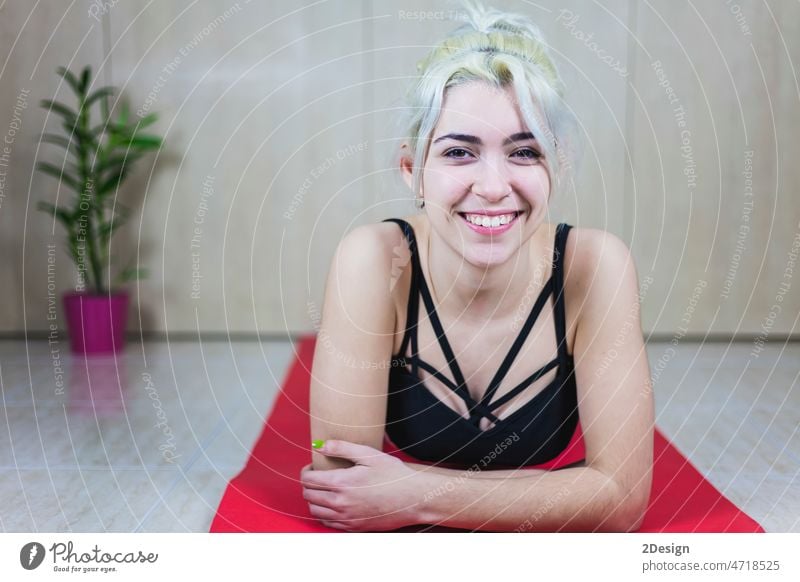 Young attractive slim athletic woman in sportswear is lying on a mat, looking at the camera and smiling athlete person abs exercise exercising fit fitness floor