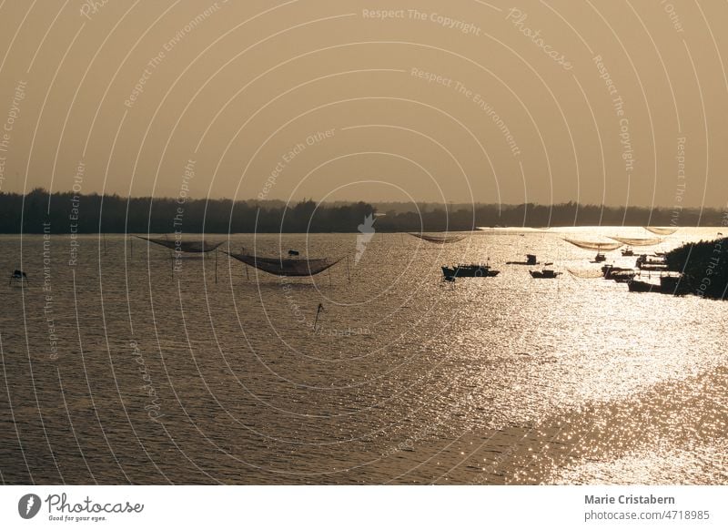 Aerial view, silhouettes of traditional lift nets and fishing boats during the sunset at Thanh Nam Fishing Village in Hoi an Vietnam aerial view drone shot