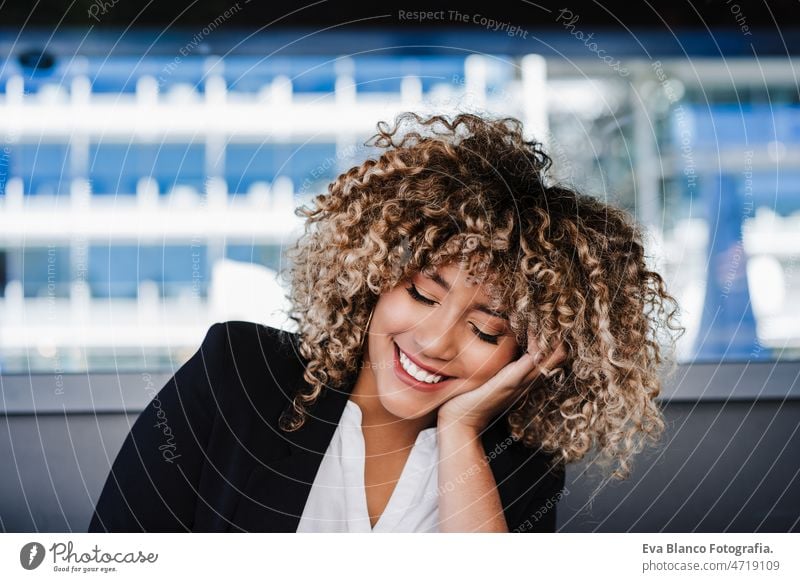 confident hispanic business woman in cafe with eyes closed. tech and lifestyle laptop computer afro working networking drinking coffee terrace outdoors goggles