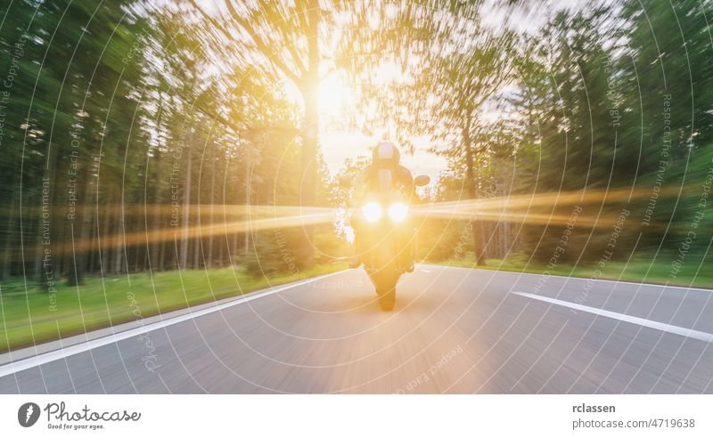 motorbike on the forest road riding with spotlights. driving on the empty road on a motorcycle tour at sunset. copyspace for your individual text. fun jacket