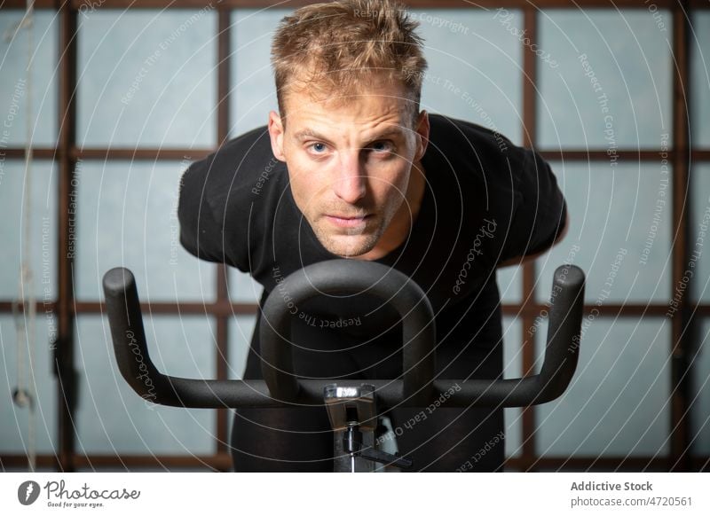 Confident man exercising on cycling machine in gym sportsman cycle exercise training workout determine confident fit male fitness athlete physical activity