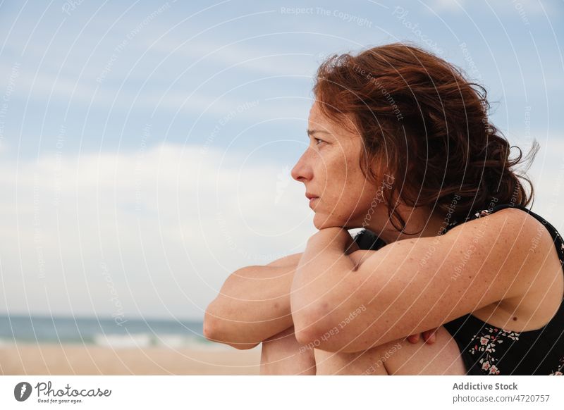 Side view of dreamy woman sitting on beach shore sea seashore recreation pastime leisure rest tourist resort sand seaside seacoast water ripple feminine style