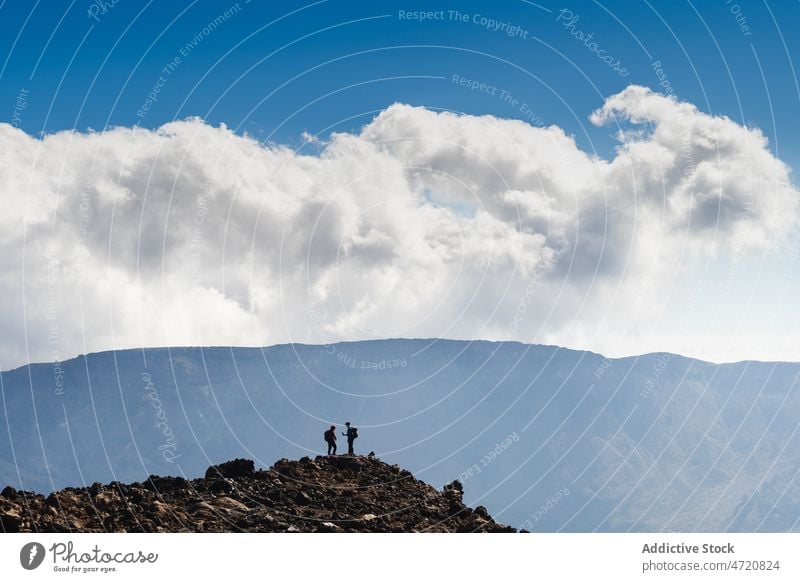 Travelers standing on rocky edge in mountainous terrain during hike traveler explore adventure slope extreme trip person nature range cliff tourism hiker