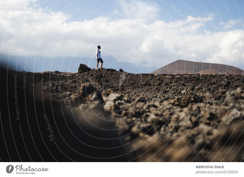 Man standing in volcanic valley during trip man tourist vacation tourism photo camera adventure desert explore male serious nature destination environment