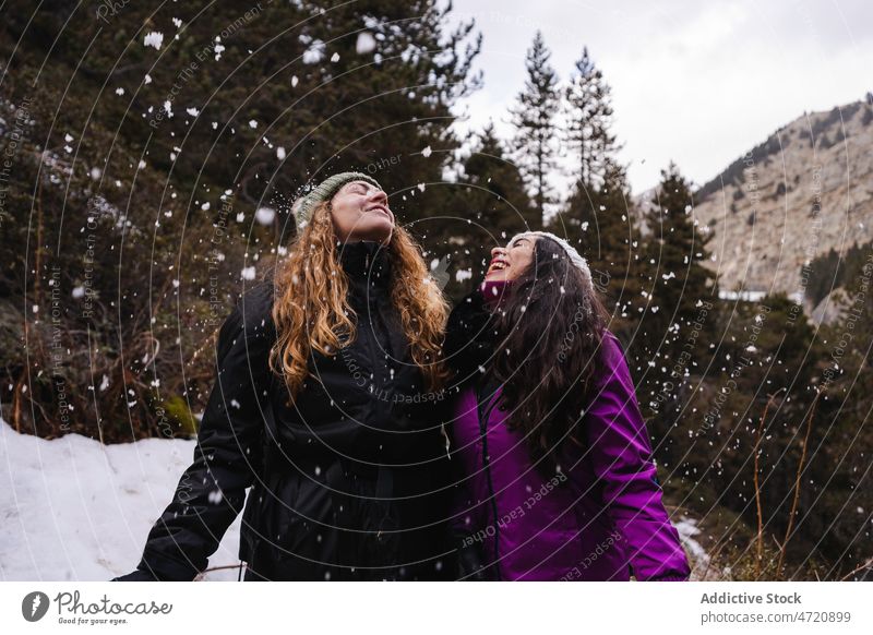 Cheerful women under falling snow friend traveler winter hiker snowfall journey pastime highland having fun leisure friendship bonding trip activity wanderlust