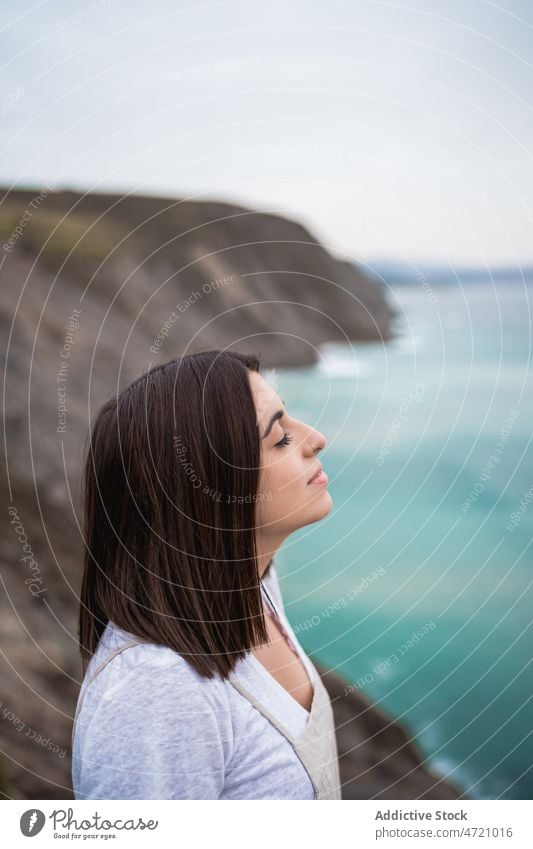 Woman standing on rocky seashore woman coast nature pastime enjoy trip leisure adventure travel seaside feminine admire eyes closed pleasure recreation smile