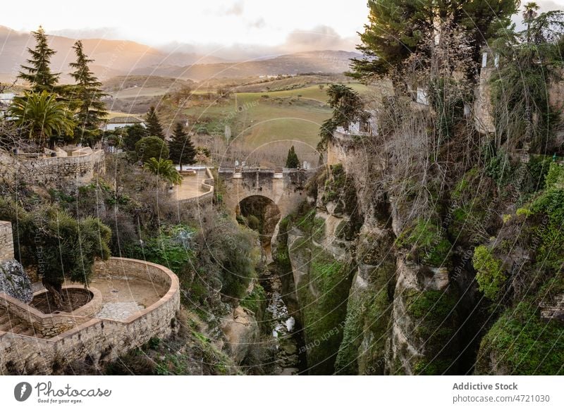 Picturesque scenery of ancient bridge in gorge at sundown landscape nature cliff architecture sunset river sightseeing heritage mountain historic breathtaking