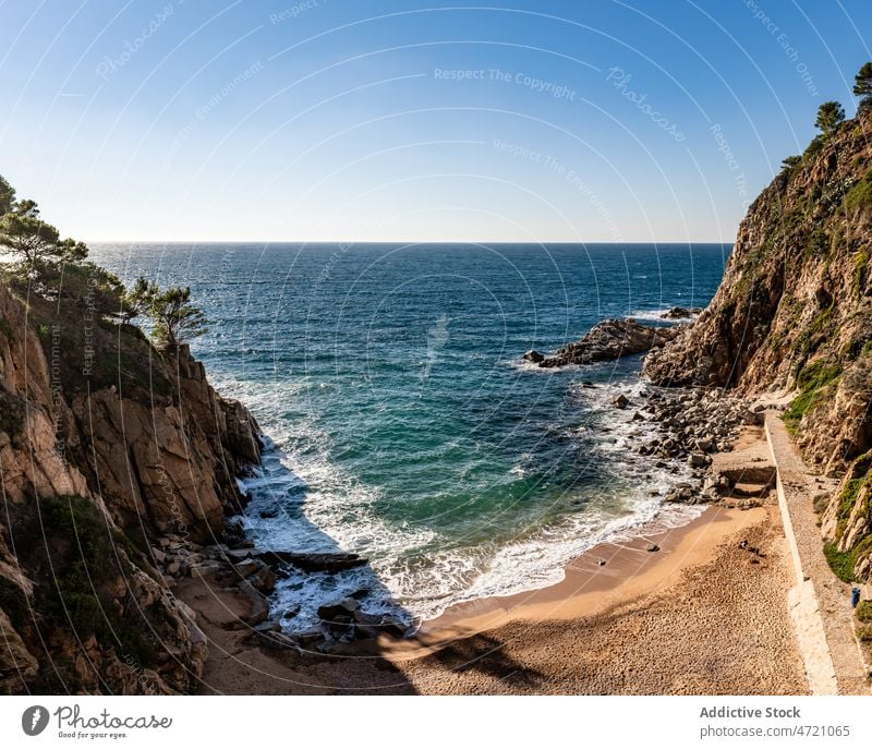 Rocky cliffs near wavy ocean in sunlight seascape seaside blue sky shore foam beach scenic scene amazing ripple idyllic coast spain girona rocky formation