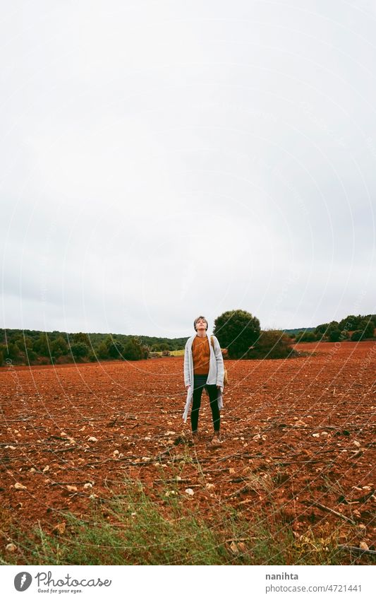 Middle age woman alone in nature in a cold autumn day outdoors adventure wanderlust short hair wool warm clothes lifestyle explore field earth fall lonely calm