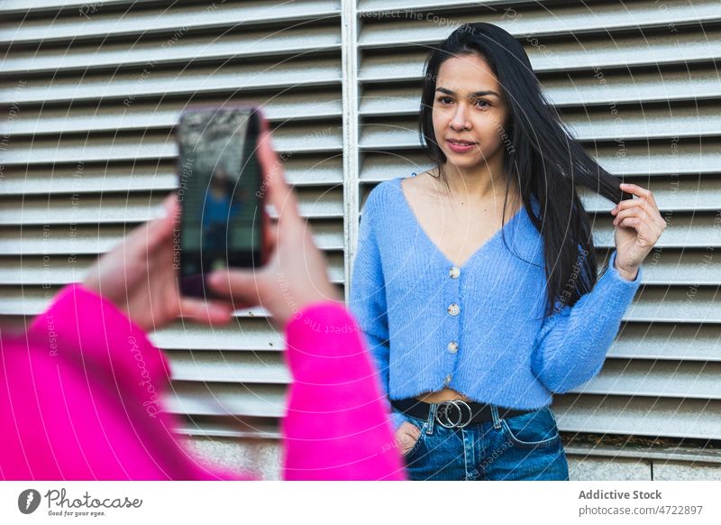 Faceless person taking photo of Hispanic woman take photo photographer smartphone street capture wall photography style feminine screen moment memory gadget