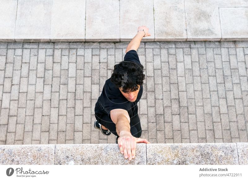 Man holding hand to wall and hanging man training street fit athlete city male guy parkour exercise fitness border sportsman urban workout strong stone activity