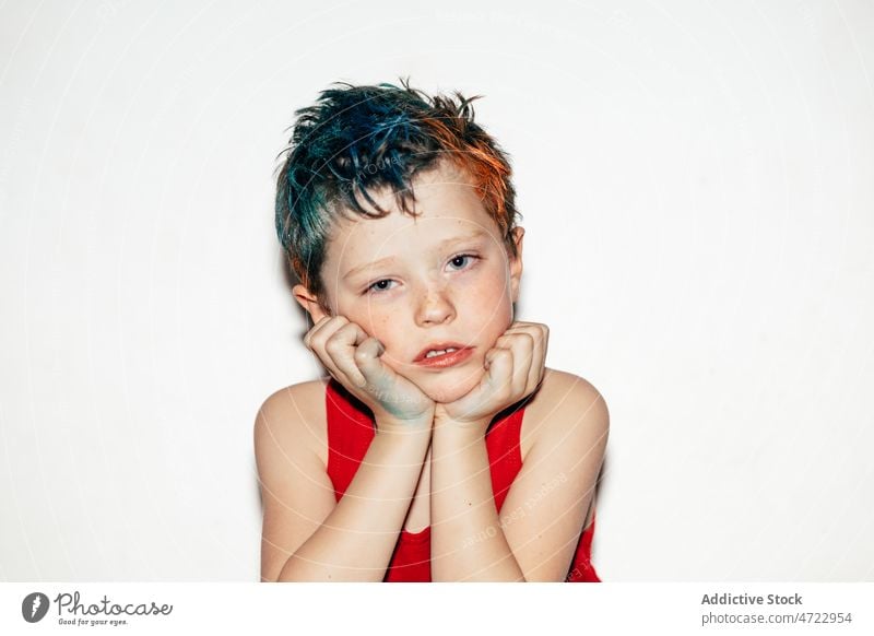 Bored boy with dyed hair looking at camera child sad bored kid naughty mischievous rebellious portrait disobedient unruly recalcitrant serious room light