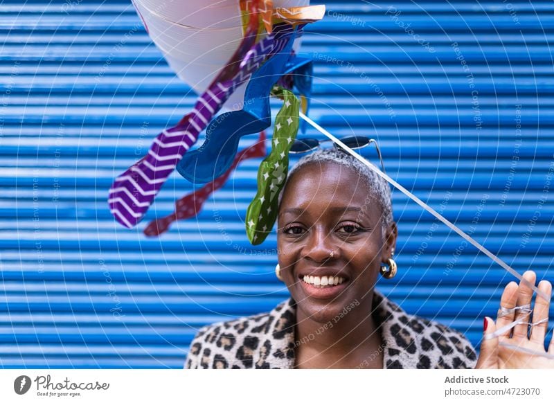 Black woman with cloud balloon near wall raining street city style pastime urban black african american short hair female lady summer town trendy coat building