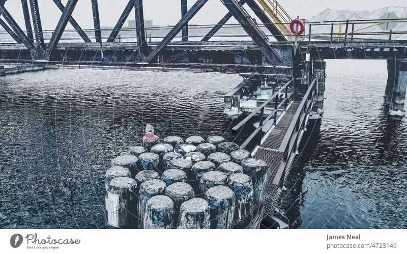 Snow falls in early dawn at the old historic swing bridge with the walkway extending out track rail railing water frost day pillar snow post morning crossing