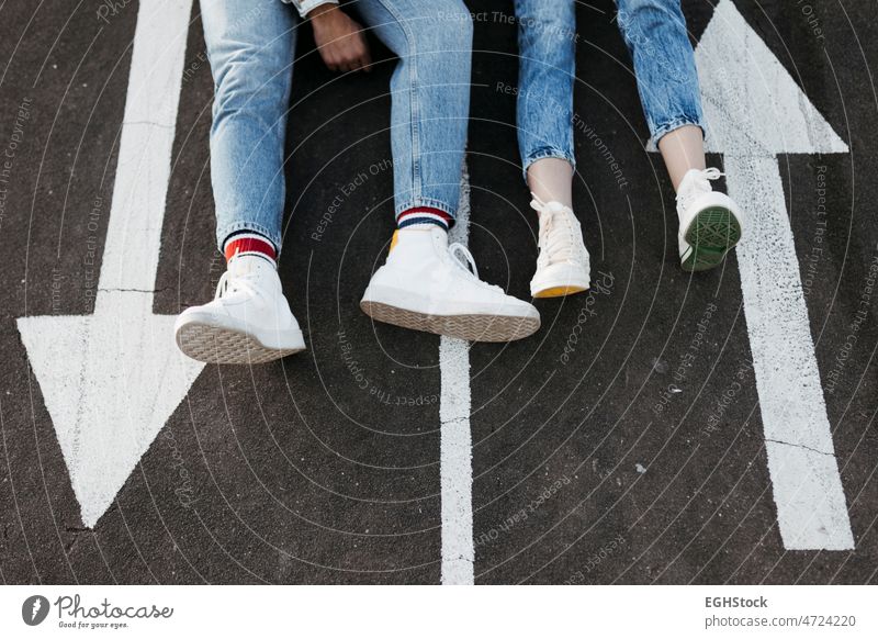 Unrecognizable young couple sitting between the signs on the floor of a skate park unrecognized unrecognizable boyfriend girlfriend asphalt asphalted happy