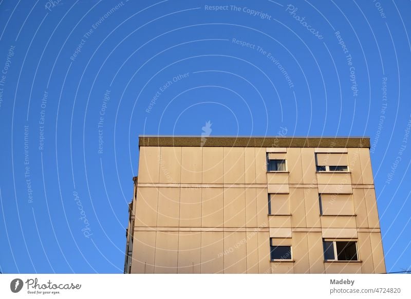 High-rise building in natural colours with roller shutters in front of the windows as sun protection against the blue sky in the light of the setting sun at the Hanauer Landstraße in the Ostend of Frankfurt am Main in Hesse