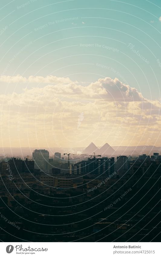 Vrtical shot of the great Giza pyramids in the distance, seen from Salah Al Din castle area. Huge city overshadowed by the amazing distant landmark dusk time