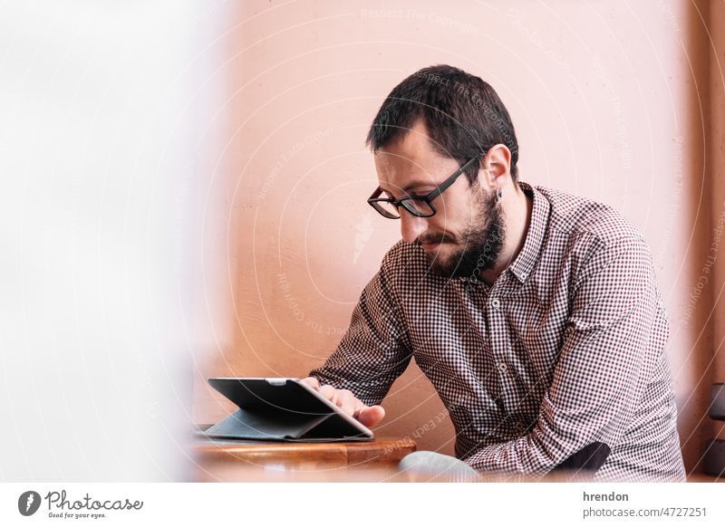 young businessman working on his tablet in a cafe shop home office young adult worker lifestyles small business laptop desk computer technology business person