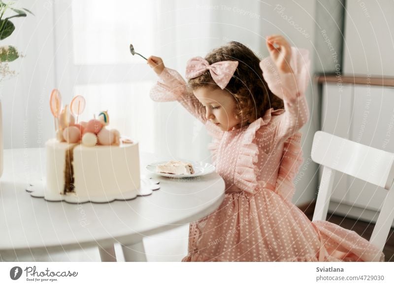 Cute little girl eats a birthday cake with a spoon on her birthday child pretty home happy kid fun sweet food dessert beautiful party portrait childhood funny