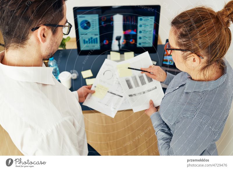 Business colleagues discussing financial data working together in office. People entrepreneurs working with charts and tables on computer. Two people working together