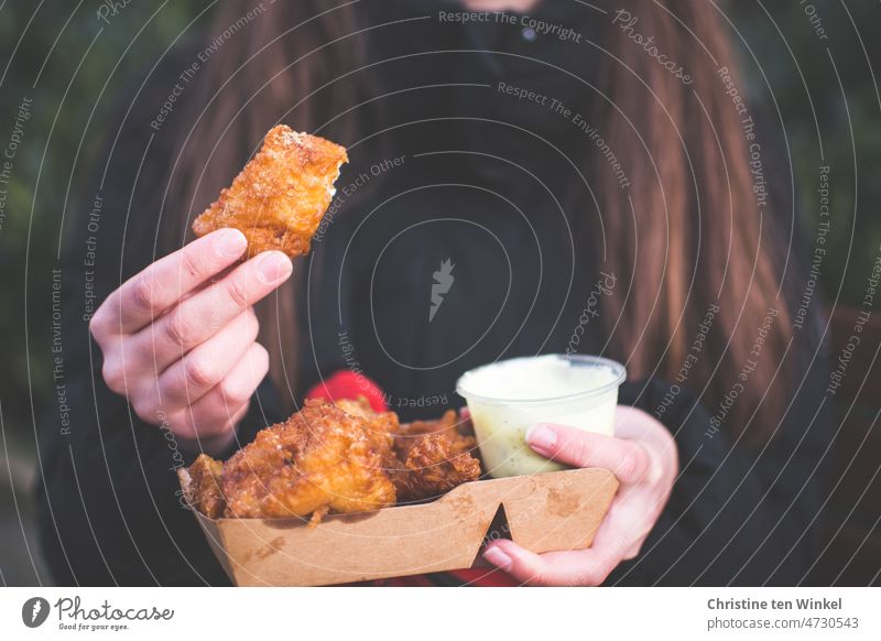 A young woman holds kibbeling with remoulade from Dutch fish cart in her hands Kibbling Fried Fisch Fish Nutrition Healthy Eating for sale out of doors Food