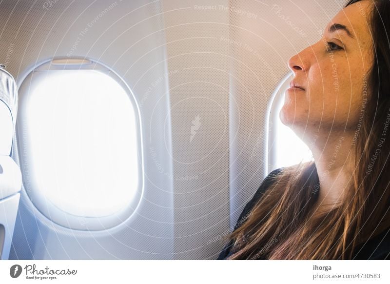 young woman sitting in airplane seat by window adult aeroplane aircraft airline airport beautiful business cabin casual comfortable female flight fly girl