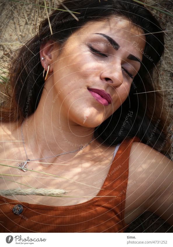 lying woman with blades of grass portrait Closed eyes To enjoy Dream Feminine warm sunny earring Long-haired Woman Smiling Dark-haired close Nature tranquillity