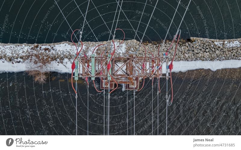 Old rusty power line tower on river rock water red drone united states cable outdoors aerial view tall stone winter climate component flowing water weather