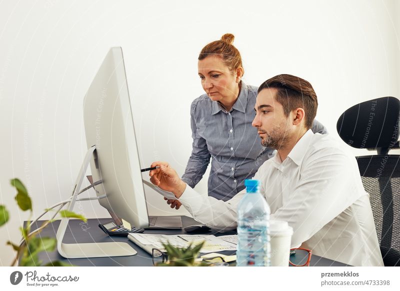 Business colleagues discussing financial data working together in office. People entrepreneurs working with charts and tables on computer. Two people working together