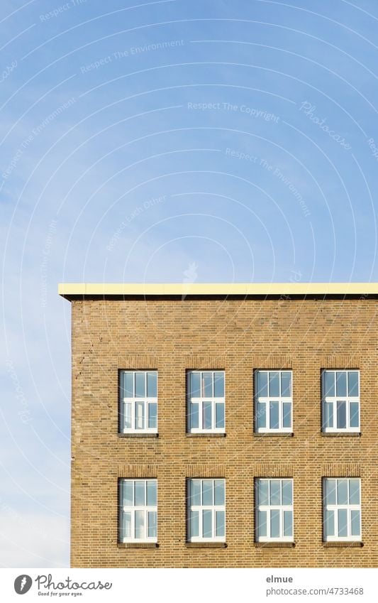 Partial view of industrial building with windows, clinker facade and flat roof against blue sky / work Industrial building Plant building Window labour bricks