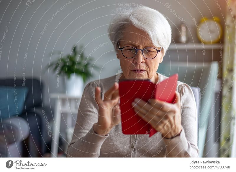 Senior woman using mobile phone at home glasses eyeglasses spectacles alone domestic life elderly female grandma grandmother grey hair house indoors lifestyle