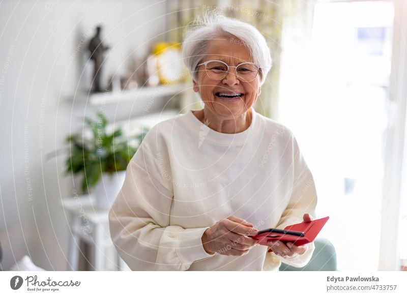 Portrait of smiling senior woman at home glasses eyeglasses spectacles alone domestic life elderly female grandma grandmother grey hair house indoors lifestyle