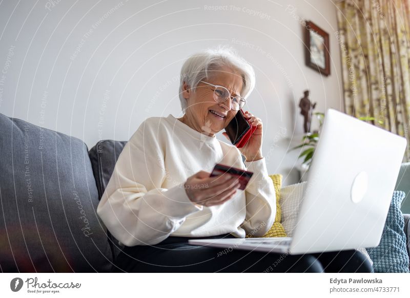 Senior woman doing online shopping on laptop at home glasses eyeglasses spectacles alone domestic life elderly female grandma grandmother grey hair house