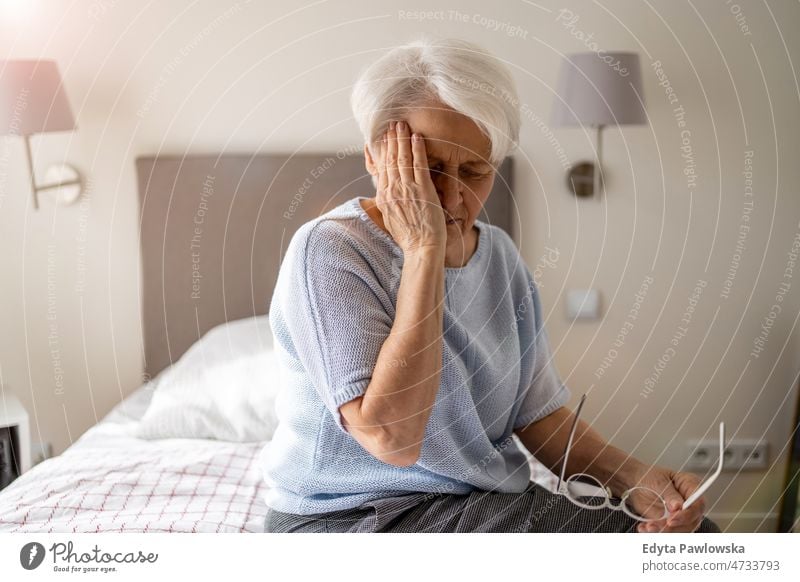 Senior woman suffering from a headache alone at home domestic life elderly female grandma grandmother grey hair house indoors lifestyle mature old older