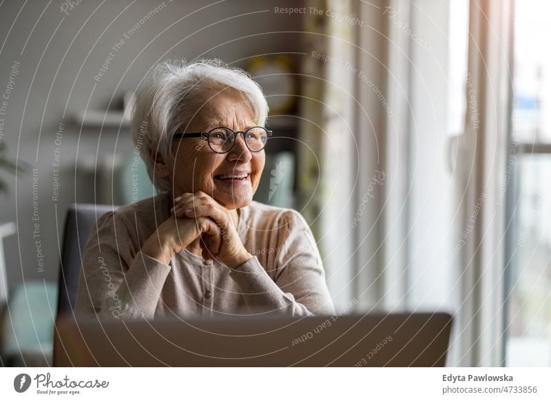 Portrait of smiling senior woman at home glasses eyeglasses spectacles alone domestic life elderly female grandma grandmother grey hair house indoors lifestyle