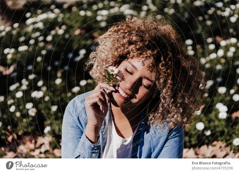 smiling hispanic woman with eyes closed in park enjoying sunny day. Spring flowers background dancing curvy body positivity afro happy spring size portrait