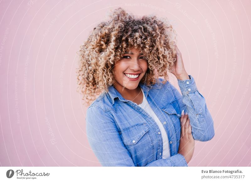 portrait of confident curvy hispanic woman outdoors in spring. pink wall. Body positivity body positivity size happy afro smiling city eyes closed