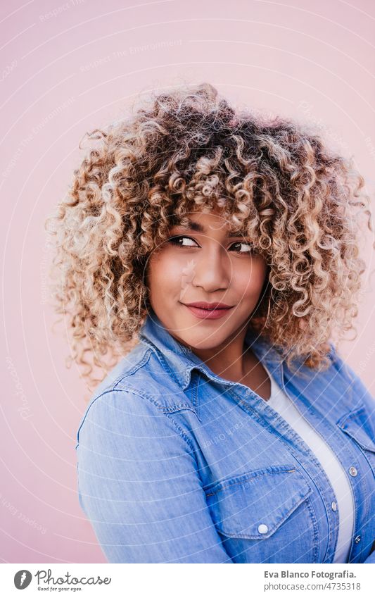 portrait of confident curvy hispanic woman outdoors in spring. pink wall. Body positivity body positivity size happy afro smiling city eyes closed