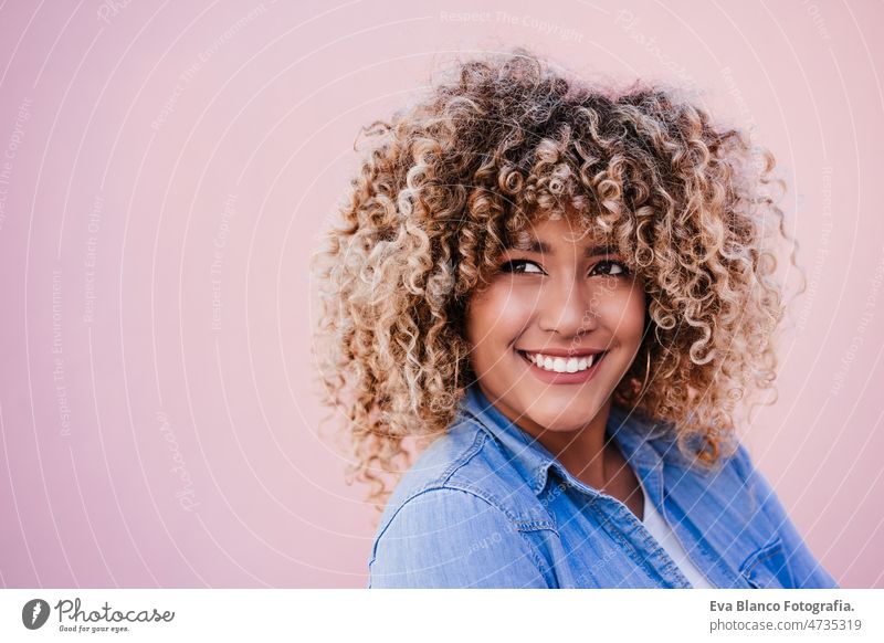 portrait of confident curvy hispanic woman outdoors in spring. pink wall. Body positivity body positivity size happy afro smiling city eyes closed