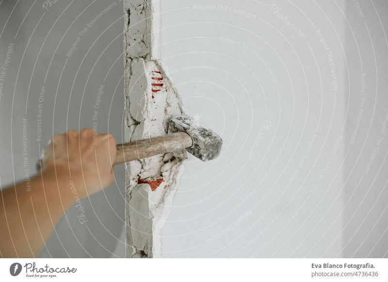 unrecognizable person holding hammer to demolish wall at construction site. Home renovation hand worker debris rubble home demolition nobody ladder bricks