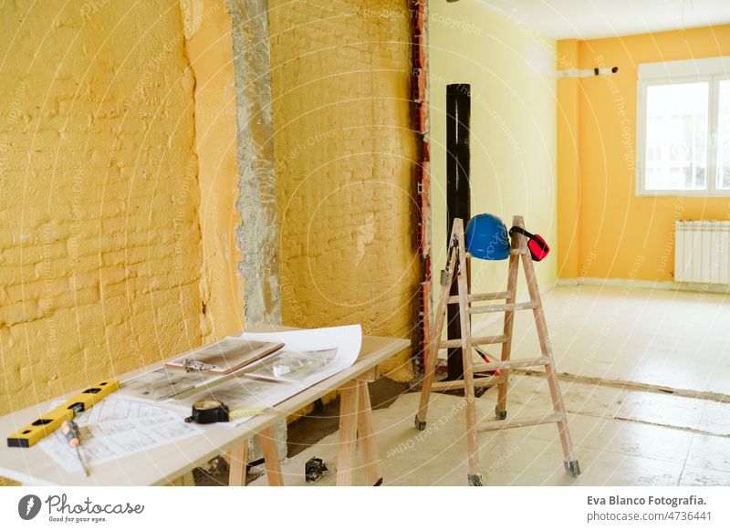 blueprints, ear defenders, protection glasses and tools on architect workspace at construction site home level meter insulating real state house yellow table