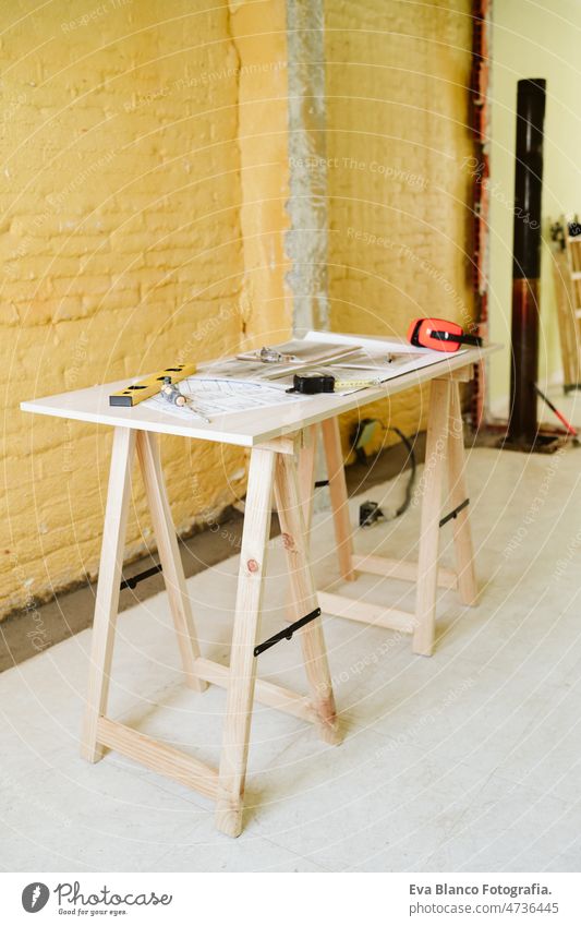 blueprints, ear defenders, protection glasses and tools on architect workspace at construction site home level meter insulating real state house yellow table