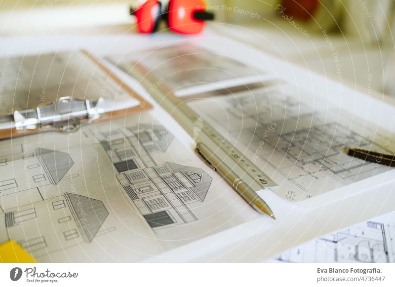 top view of blueprints, ear defenders, level and tools on architect workspace at construction site home meter insulating real state house yellow table build