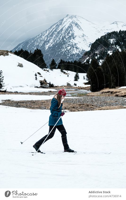 Active female skier against snowy mountain woman ridge ski resort vacation sporty winter cold active freeze frozen season frost warm clothes outerwear lady